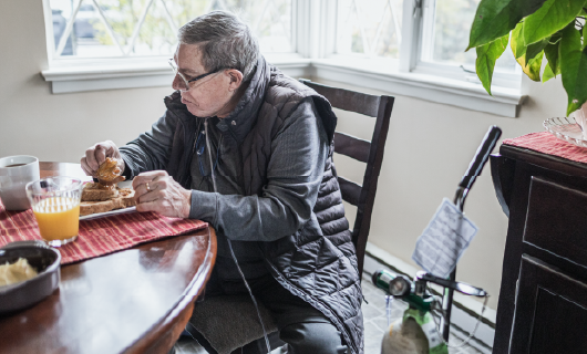 a person with an oxygen tank sitting to eat breakfast