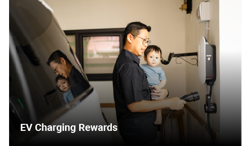 a man holding a baby while looking at a residential electric vehicle charger